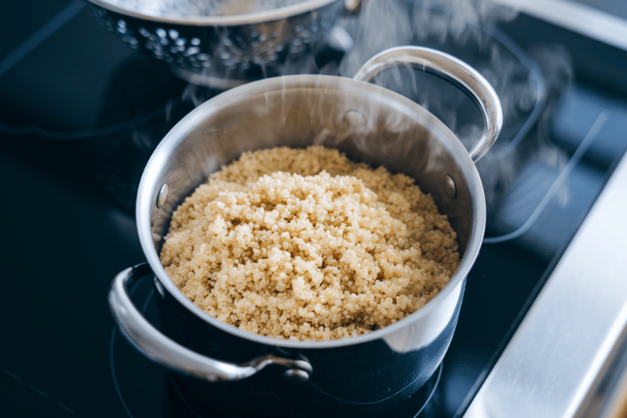 A top-down shot of quinoa being cooked in a small pot, with visible steam indicating it’s nearing readiness.